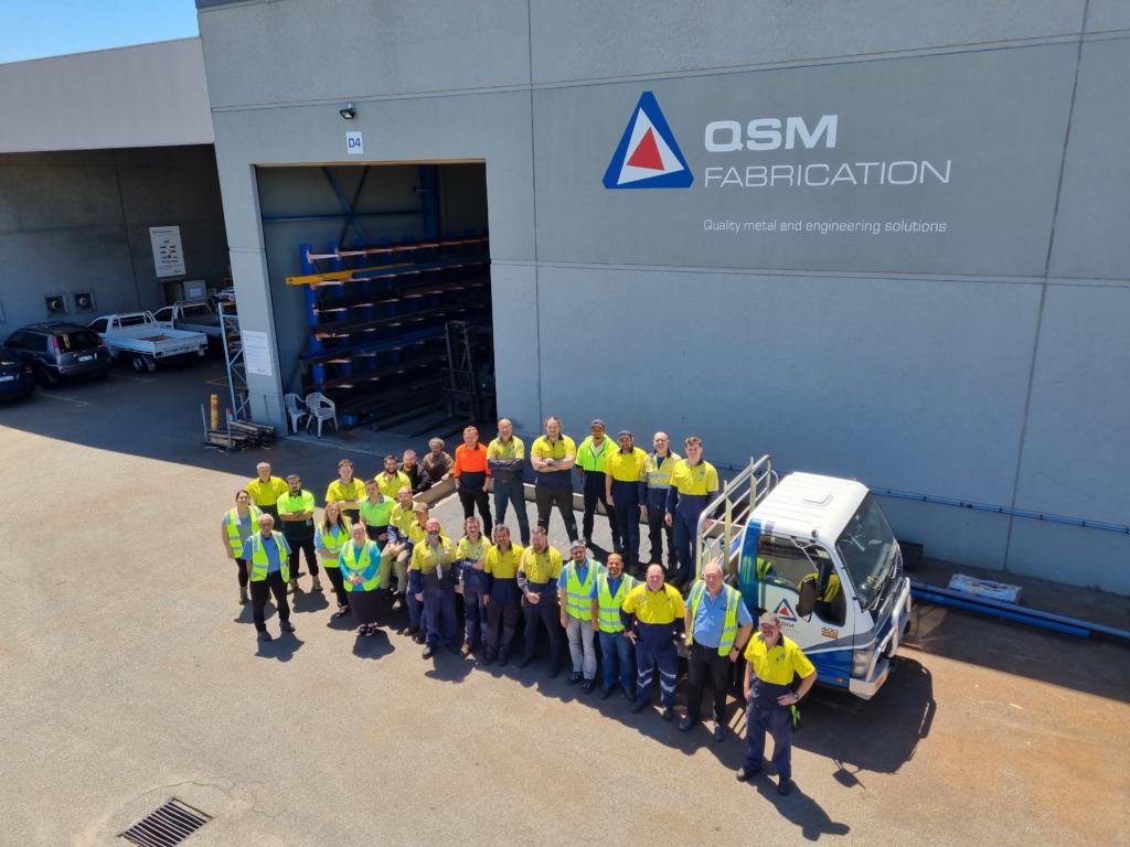 QSM team lined up alongside truck outside warehouse